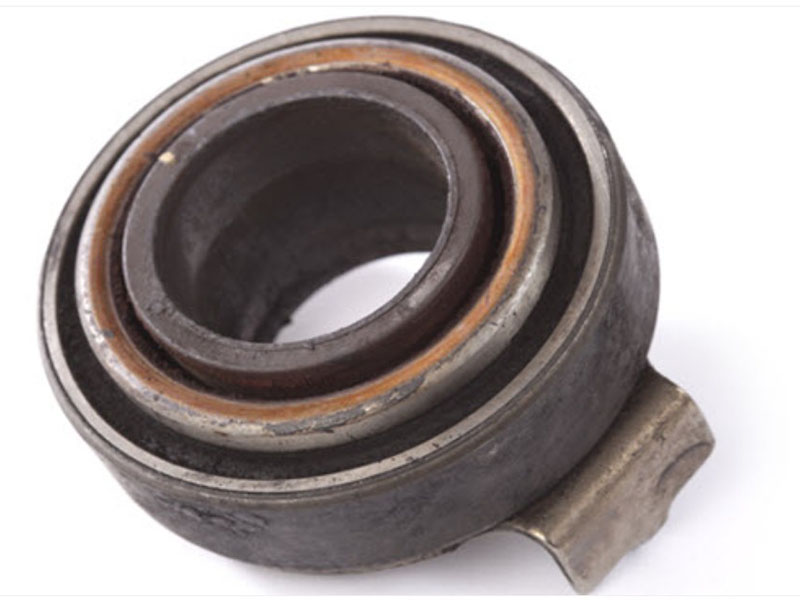 Worn clutch release bearing with pitted surface and metal debris showing common failure symptoms like squealing noise, grinding, pedal vibration, and difficulty shifting gears