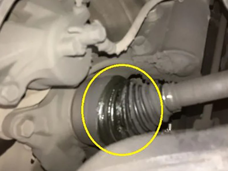 Comparison of intact versus torn CV boot on tripod joint with grease splatter, showing contaminated needle bearings and worn roller tracks from moisture and debris ingress